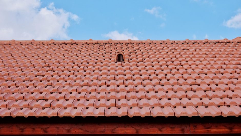 Czerwony dach kryty dachówką ceramiczną na tle błękitnego nieba